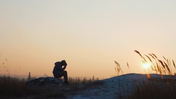 美しい夕日を背景に高い山の上の若い男 日没時に山の上の男 悲しみやうつ病の男 — ストック動画