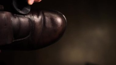 Yumuşak odaklı adam erkek deri ayakkabılarına bakıyor, eskimiş ayakkabılara kahverengi krem sürüyor, yakın plan, ayakkabıcı ayakkabıları siliyor.