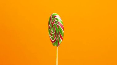Turuncu arka planda lolipop. Karamel renkli şeker dönüyor