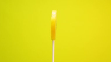 Sarı arka planda meyveli lolipop. Karamelli limon şekeri dönüyor.