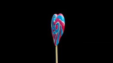 Çubuktaki karamel lolipop kalp siyah arka planda dönüyor. Şeker kamışı sarmal kopyalama alanı
