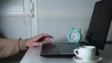 Serbest çalışan elini klavyeye vuruyor, ofisteki internet işçisi. Evde çalışan, düşünceli genç bir adamın elleri portatif bir dizüstü bilgisayarın monitörüne bakıyor.