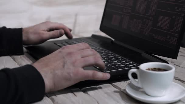 プログラマーは家庭の概念で働く 男がテーブルの上にコーヒーを飲みながらノートパソコンのキーボードを入力している フリーランスはノートパソコン付きのデスクで働いています — ストック動画