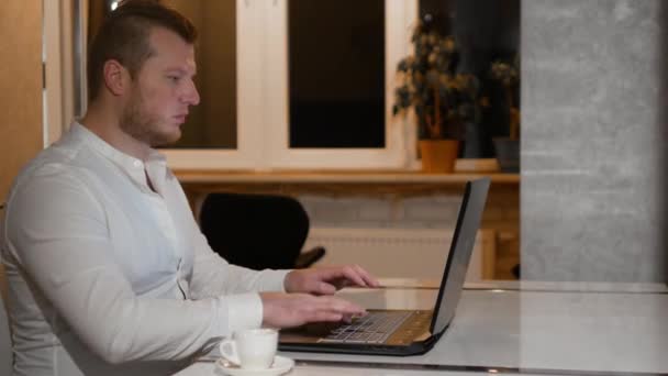 셔츠를 커피를 마시고 프리랜서는 집에서 컴퓨터 키보드로 인터넷을 사용하여 노트북으로 — 비디오