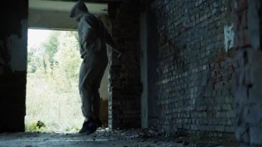  Genç bir adam yıkılmış bir binada ip atlıyor.