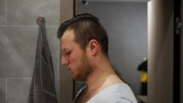 一个年轻人在浴室里用剃须刀 一个男人在家里或宾馆里用剃须刀刮胡子 — 图库视频影像