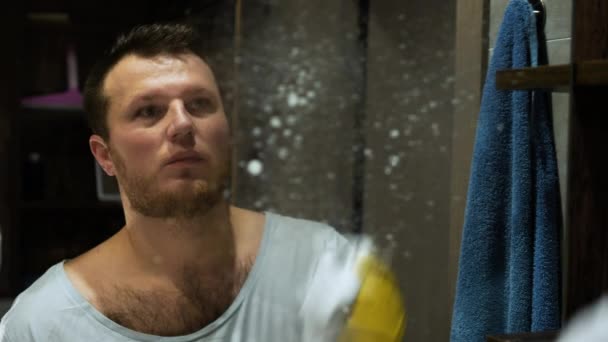 남자가 세척기로 욕실에서 거울을 아파트의 거울에서 먼지를 — 비디오