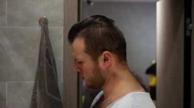 Burun kıllarını yolmak. Genç bir adam banyoda aynanın karşısında dikilirken burnundan bir şey çıkarır. Sabahları aynaya bakan komik bir genç adam.