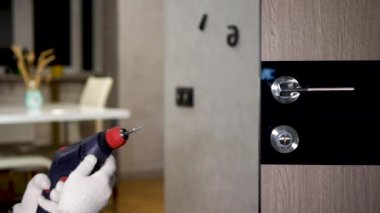 Ön kapıya bir kilit takıyorum. Özel üniformalı bir marangoz ön kapının kilidini tamir eder. Tornavidalı bir adam kapı tokmağını yerleştirir.