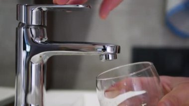 Bir el musluğa bardak getirir. Bir bardağa filtrelenmiş içme suyu dök. Kişi su tüketir.