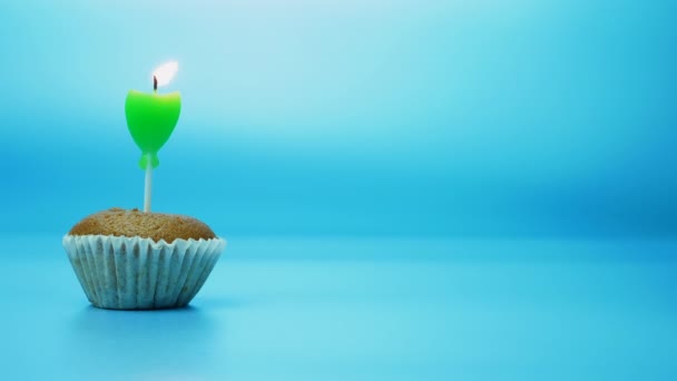 青い背景に緑の燃えるお祝いのろうそくとカップケーキを焼く — ストック動画