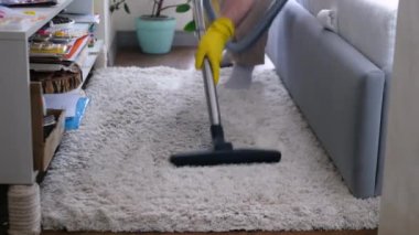 Adamın biri dairede yün bir kilim süpürüyor. Dairelerdeki odaları temizliyorum. Halıyı elektrikli süpürgeyle temizliyorum..