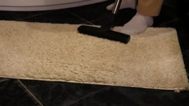 Adam banyodaki beyaz halıyı temizliyor. Dairede halı temizliği.