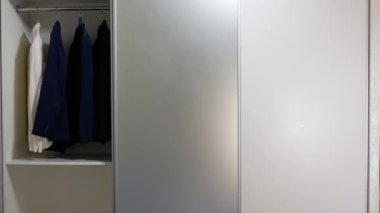 Elbiseli gardırop. Gardıroptaki sürgülü kapılar, kompartımanın sürgülü kapılarını açma ve kapatma sistemi. Giysiler için depo alanı. Çağdaş gardırop.