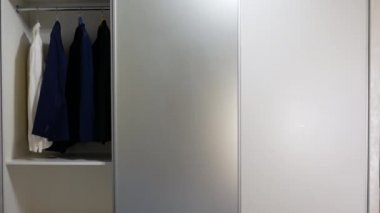 Elbiseli gardırop. Gardıroptaki sürgülü kapılar, kompartımanın sürgülü kapılarını açma ve kapatma sistemi. Giysiler için depo alanı. Çağdaş gardırop