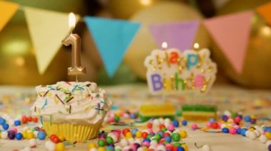 Incredibly beautiful 1 year old child birthday background, cream cupcake with burning candle, sparkler and balloons in the background. 1 year old baby birthday background video.