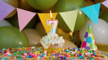 7 yaşındaki bir çocuk için güzel bir doğum günü tebriği, balonların arka planında mumlar ve doğum günü süslemeleri olan kek süslemeleri.