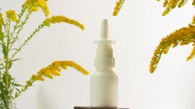 Beyaz arka planda şişe burun spreyi, homeopatik tedavi, şifalı bitkilere dayalı tıbbi burun spreyi bir masada dönüyor.