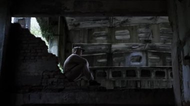 Terk edilmiş bir binada üzgün bir adam, depresif bir adam. Sinema tonu. Genç bir adamın hayatındaki sorunlar