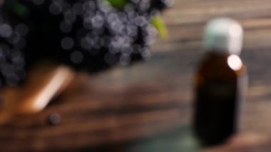 Ahşap bir tahtanın üzerinde saman sepetinde siyah mürver, böğürtlen suyundan sıvı içeren bir ilaç şişesi. Homeopati.