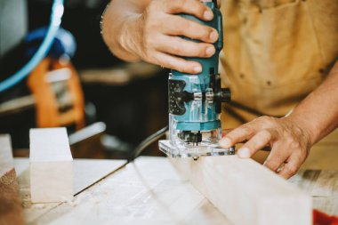 Marangoz malzemeyi çıkarmak ve atölyedeki ahşap yamayı kesmek için Router Trimmer 'ı kullanır. seçici odak