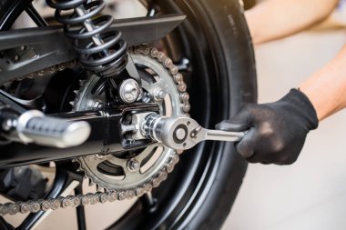 Arka Motorsiklet Tekerleği 'ni kaldırmak ve değiştirmek için anahtar ve soket kullanan tamirci, tamirat, garajda motosiklet konseptini onarmak.