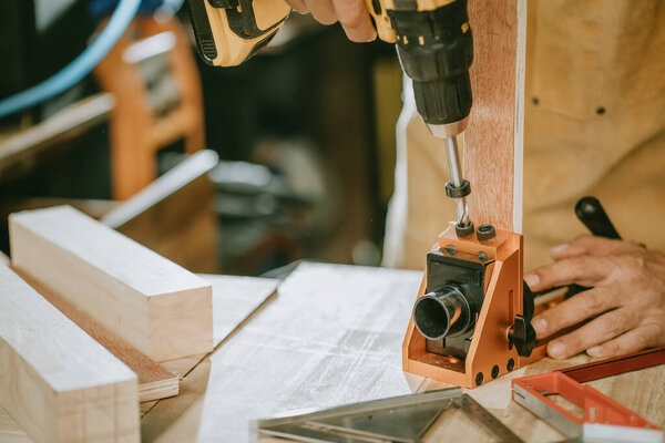 Столяр использует Cordless Drill и карманные отверстия джиг или зубчатый джиг, привод винта на деревянную пластину, DIY производитель и деревообрабатывающая концепция. селективный фокус