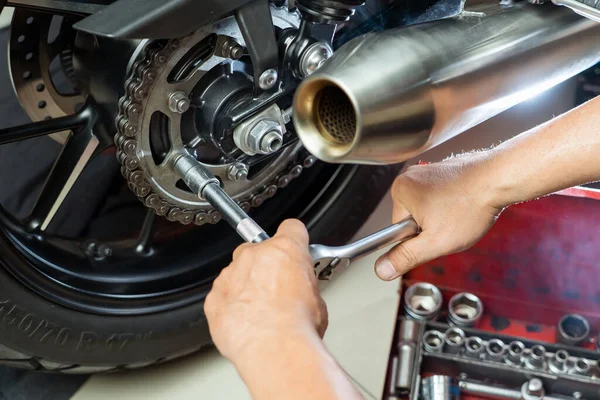 Motosiklet kazığında anahtar ve soket kullanan tamirci. Motosiklet garajında bakım ve onarım konsepti. Seçici odaklanma 