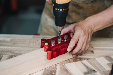 Marangoz tahta plaka üzerinde güçlü eklemler yapmak için matkap ucu ve merkez jig veya cep delik jig alet kullanır. ahşap işçiliği kavramı. Seçici odaklanma.