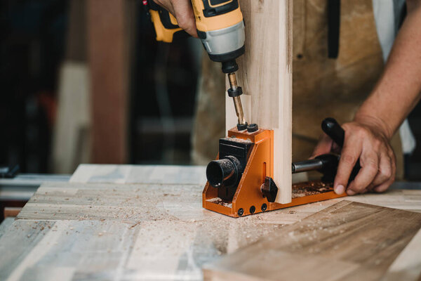 плотник использовать сверло и центрируя дюбеля джиг или карманные отверстия джига инструмент для создания сильных соединений на деревянной пластины. Деревообрабатывающий концепт.