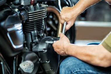 Garajda motorda anahtar ve soket kullanan bir tamirci. Tamirat, motosiklet konsepti. Seçici odaklanma.