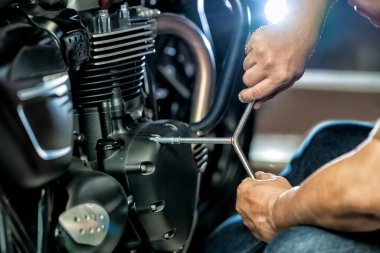 Garajda motorda anahtar ve soket kullanan bir tamirci. Tamirat, motosiklet konsepti. Seçici odaklanma.