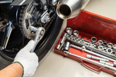 Motosiklet kazığında anahtar ve soket kullanan tamirci. Motosiklet garajında bakım ve onarım konsepti. Seçici odaklanma 