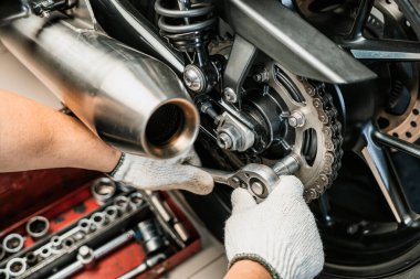 Motosiklet kazığında anahtar ve soket kullanan tamirci. Motosiklet garajında bakım ve onarım konsepti. Seçici odaklanma 