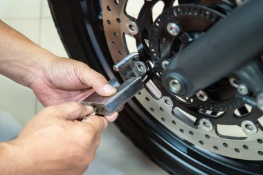 Motosiklet sahibi, motosiklet fren, motosiklet güvenliği ve hırsızlıkla mücadele konseptine asma kilit ve kilit taktı