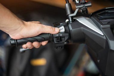 Sürücü gidonu tutuyor ve motosikletin korna tuşuna basıyor, garajda motosiklet konseptini onarıyor. Seçici odak noktası