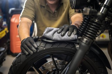 Motosikletli adam motorsikleti temizliyor, ön çamurluğa cilasını sürüyor ve cilalıyor. tamir ve bakım motosiklet konsepti.