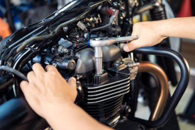 Motosikletin silindir başında anahtar ve soket kullanan bir tamirci. Tamir, garajda motosiklet konsepti. Seçici odak noktası.