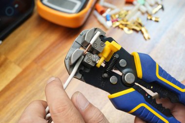 Kablo sökücüler ya da kablo sökücüler. Elektrik kablolarından izolasyonu kaldırmak için kablo sökücü tutan elektrikçi. Güvenli ve araçlar kavramı