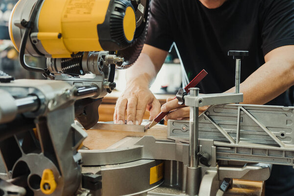 плотник использует машинную площадь и карандашную маркировку на дереве на пильном столе Miter в мастерской, DIY производителя и деревообрабатывающей концепции. селективный фокус 