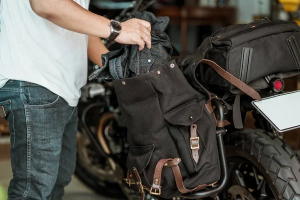 Sürücü kıyafetleri yan çantadan ya da eyerlenmiş motosiklet çantalarından alır. Motosiklet yolculuğu konsepti. seçici odak