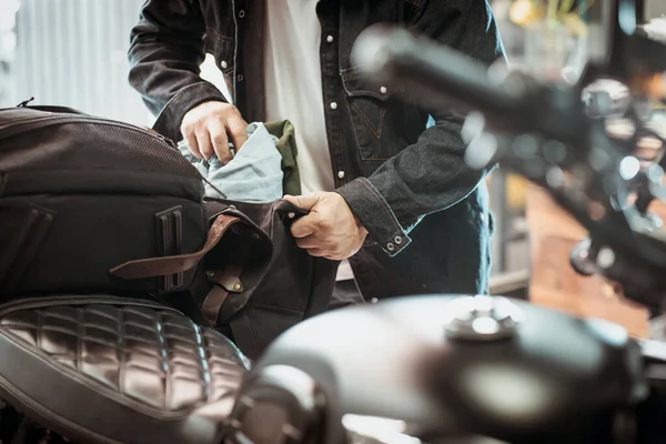 Sürücü kıyafetleri yan çantadan ya da eyerlenmiş motosiklet çantalarından alır. Motosiklet yolculuğu konsepti. seçici odak