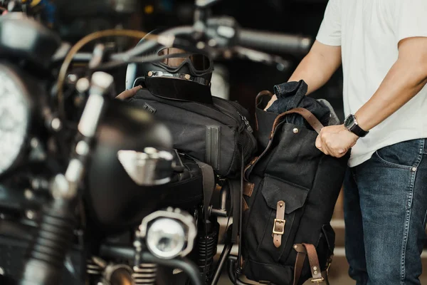 Sürücü bir motosiklet eyeri ya da bagaj destesi antika motosikletine yan çanta yükler. Motosiklet seyahati. seçici odak