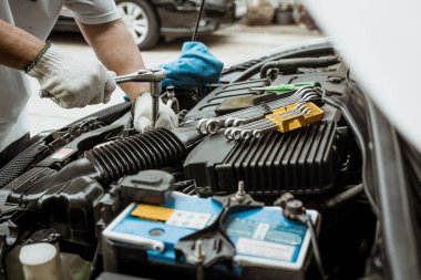 Tamirci ingiliz anahtarı ve soketi kullanıyor ve garajdaki araba motorunu tamir ediyor. Tamirat araba konsepti, seçici odaklanma.