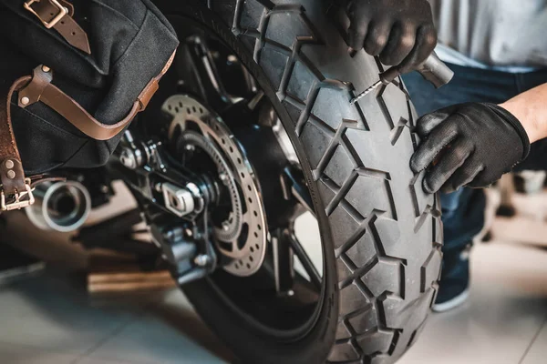 Rider use a tire plug kit and trying to fix a hole in tire\'s sidewall ,Repair a motorcycle flat tire in the garage. motorcycle maintenance and repair concept