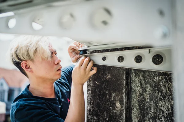 A professional electrician man is fixing Rubber Shock Absorber Vibration Isolator Mounts for Air Conditioners to reduce low-frequency noise caused by vibration