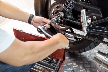 Arka Motorsiklet Tekerleğini kaldırmak ve değiştirmek için anahtar ve soket kullanan tamirci, garaj bakımında çalışıyor, motosiklet konseptini onarıyor.