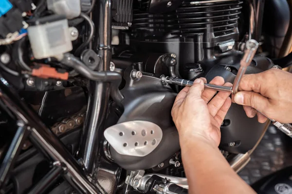 Mechanic using a Y Shape Wrench to Remove front sprocket cover on motorcycle, working in garage .maintenance and repair motorcycle concept .selective focus