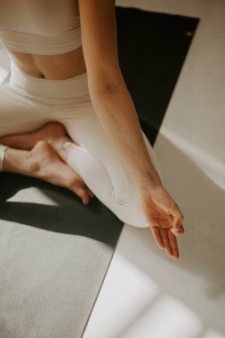 Sakin genç bir kadın meditasyon yapıyor, güzel bir yoga stüdyosunda lotus poz veriyor. Ardha Padmasana 'da oturan genç çekici kadın, Lotus meditasyonda poz veriyor, kapalı gözler, spor kıyafetleri giyiyor.