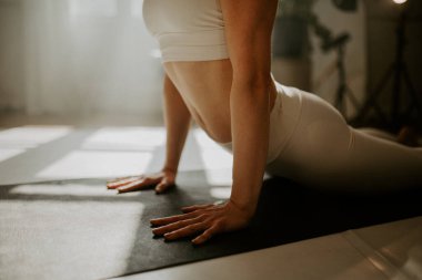 Yoga yapan, şınav çeken, sohbet eden, dandasana pozu veren spor giyinen, kapalı bir yerde yoga yapan genç bir kadın.